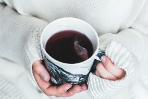 hands holding mushroom tea in a white and black teacup