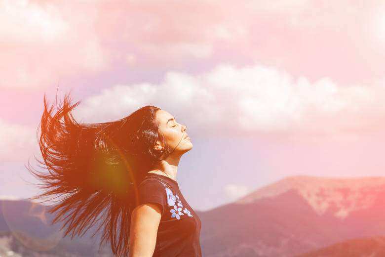 Woman with long hair standing on the top of mountain