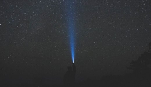 man with flashlight pointed at the sky