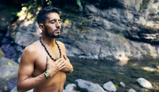 man praying with hands over heart