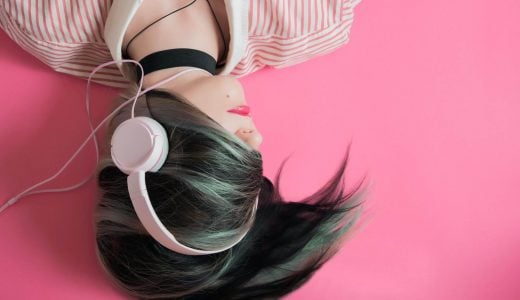 girl with headphones on pink background